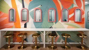 A bar area with a colorful abstract wall, multiple mirrors, and gold bar stools. - Sleeps 12+ OWA Retreat: Backyard Bowling + Dogs (Foley)