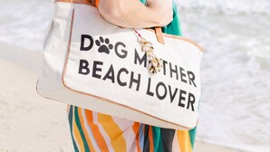 A person with a bag labeled 'DOG MOTHER BEACH LOVER' standing on a beach. - Sleeps 12+ OWA Retreat: Backyard Bowling + Dogs (Foley)