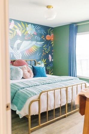 Une chambre à coucher avec un lit, une peinture murale et une fenêtre avec des rideaux.