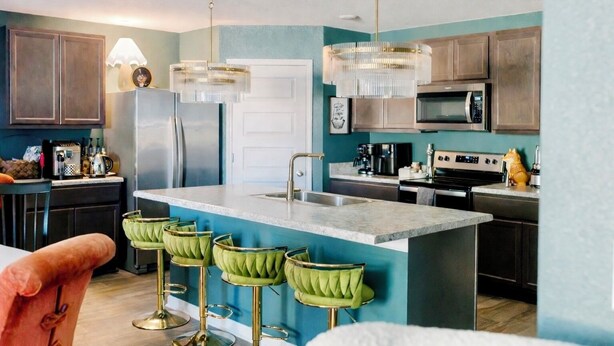A modern kitchen with a central island, bar stools, stainless steel appliances, and pendant lighting. - Sleeps 12+ OWA Retreat: Backyard Bowling + Dogs (Foley)
