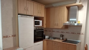 Eine kleine Küche mit Holzausstattung, integriertem Mikrowellenherd, Backofen und Spüle.