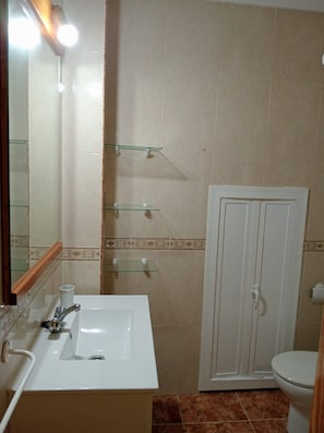 A bathroom with a white sink, mirror, and toilet. There are glass shelves above the sink and a white door to the right. - Apartment in Almeria for Family (Carboneras)