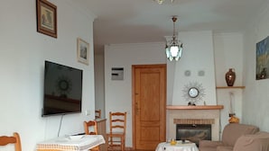 Ein Wohnzimmer mit Fernseher, Holzmöbeln, Kamin und Deckenleuchte.