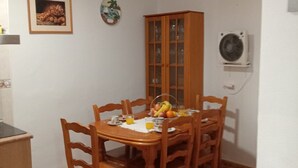 Ein Essbereich mit Holztisch, Stühlen, einem Schrank und einer Wand-Klimaanlage.