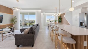 A modern kitchen with a central island, bar stools, and a dining area with a view. - Storey Lake brand new near Disney lake & club view (Kissimmee)