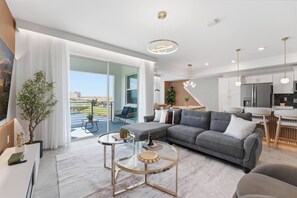 A modern living room with a sofa, coffee table, and dining area. - Storey Lake brand new near Disney lake & club view (Kissimmee)