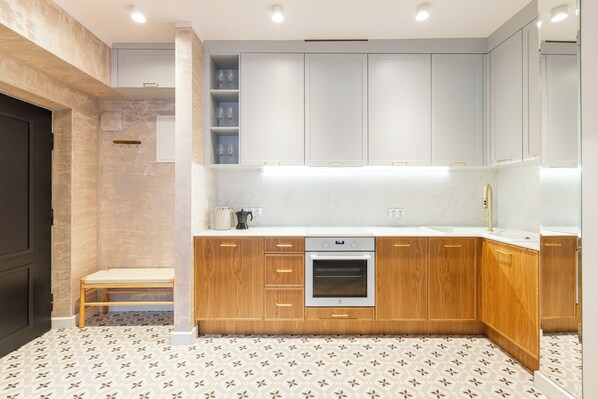 A modern kitchen with wooden cabinets, a built-in oven, and a bench. - Native Apartments Potebni 8 (Kraków)