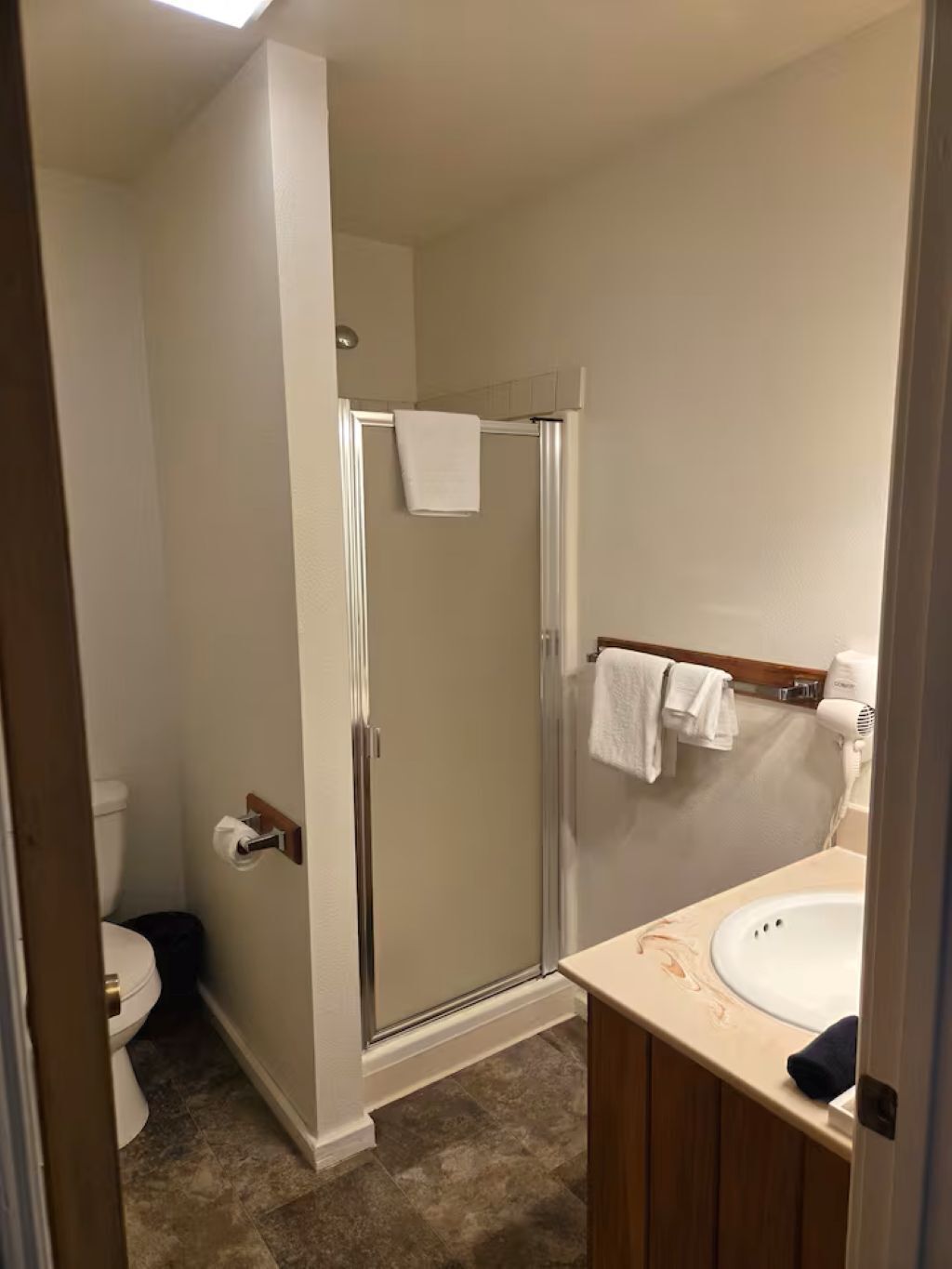 Une salle de bain avec douche, toilettes et lavabo.