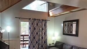 A living room with a sofa, a coffee table, a TV, a lamp, and a window with curtains.