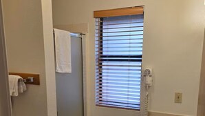 A bathroom with a shower, a sink, and a window with blinds. - Cozy Studio in Idyllwild (Idyllwild-Pine Cove)