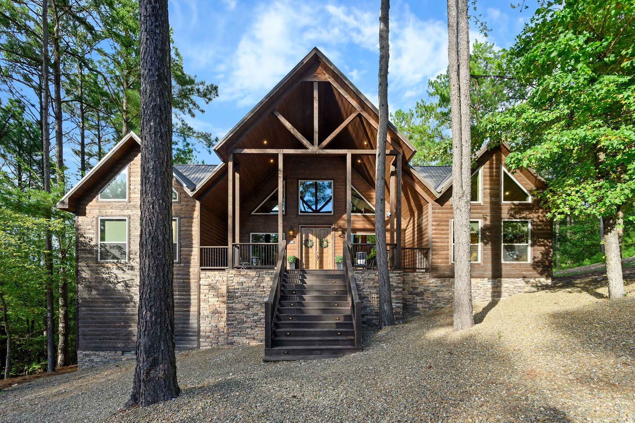 A log cabin with a central staircase, stone walls, and a large window.