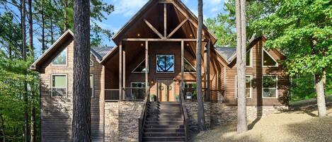 A log cabin with a central staircase, stone walls, and a large window.