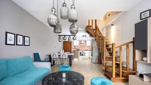 A modern living room with a sofa, a round table, and a staircase. - Charming Maisonette In Southern Suburbs (Voula)
