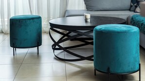 A modern living room with a round coffee table, two ottomans, a sofa, and hanging pendant lights. - Charming Maisonette In Southern Suburbs (Voula)