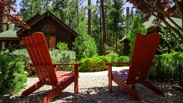 Two red Adirondack chairs facing each other with a wooden cabin in the background. - Tranquil Studio at Eagle Creek (Idyllwild-Pine Cove)