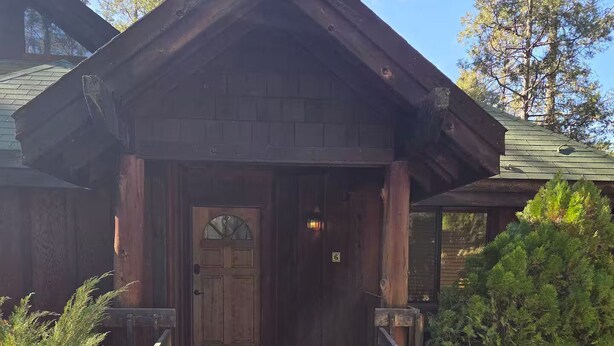 Een houten lodge met een groene houten looppad dat naar een deur leidt.