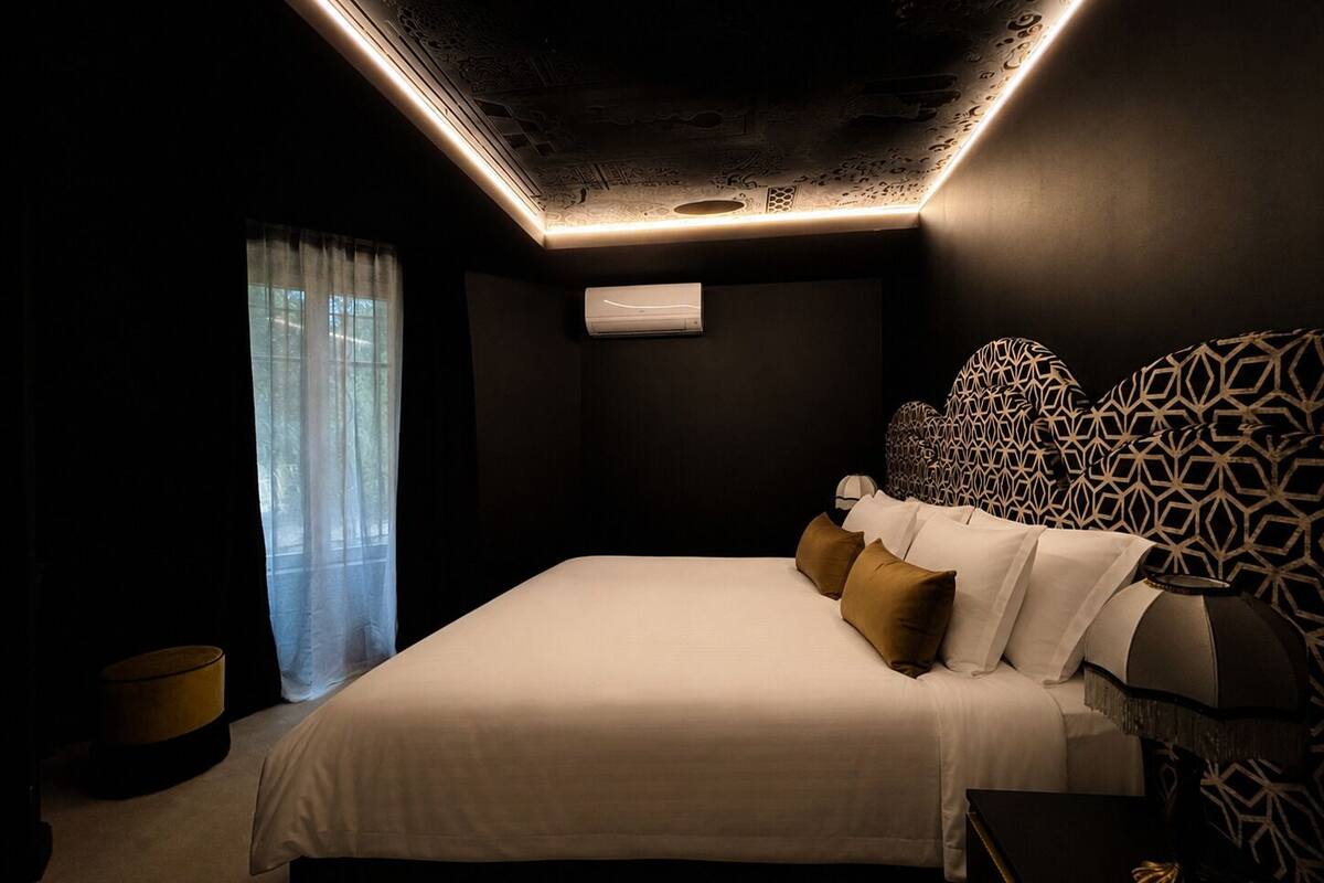 Une chambre à coucher moderne avec un lit, une tête de lit à motifs et un luminaire au plafond.