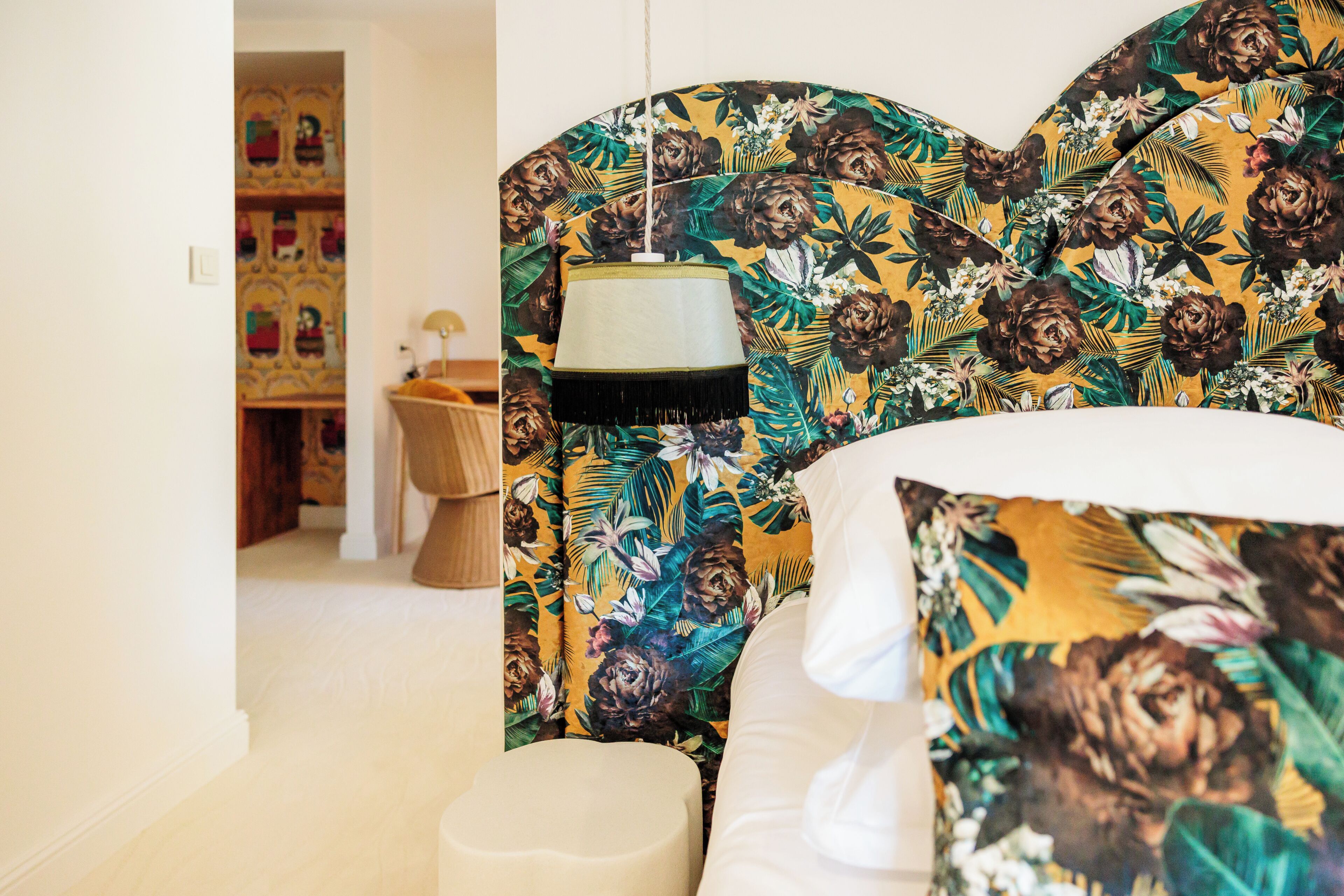 Un dormitorio con una cama, una lámpara colgante y un cabecero estampado con motivos florales.