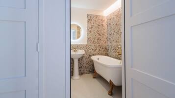 A bathroom with a white sink, a freestanding bathtub, and floral patterned tiles.