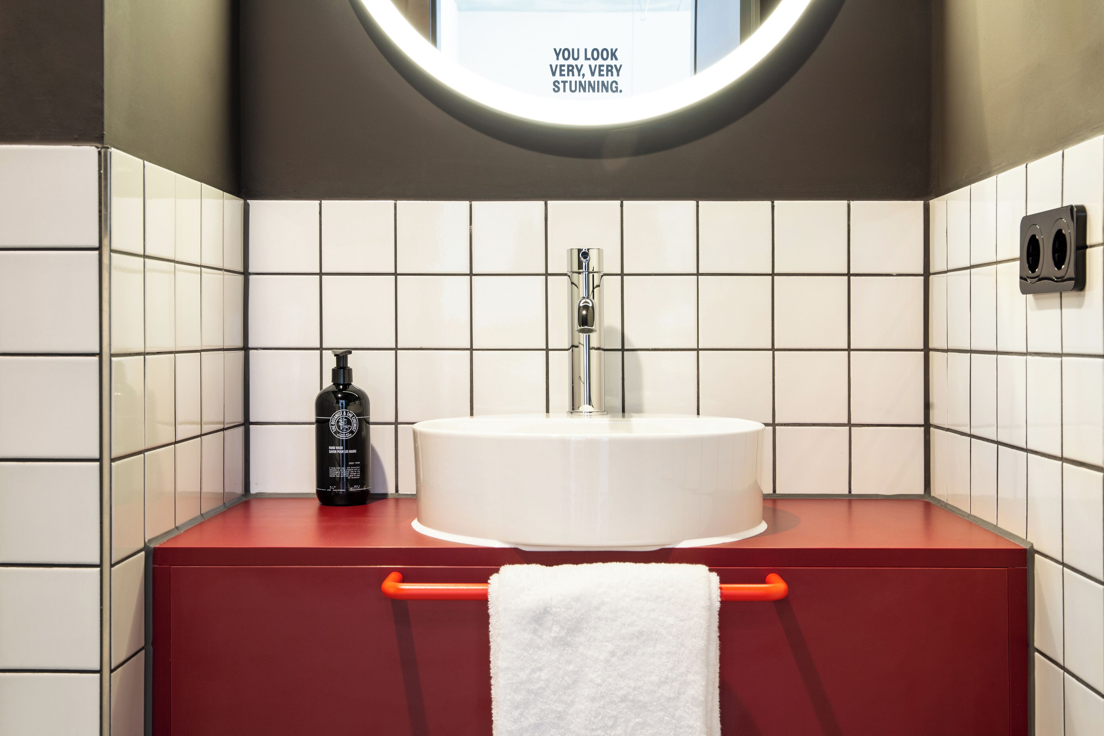 A bathroom with a round sink, a mirror, and a towel rack.