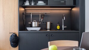 A modern kitchen with a black countertop, a sink, a coffee machine, and a stove. - STAYERY Fürth Innenstadt (Fuerth)
