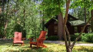 Une cabane dotée d’une véranda, entourée d’arbres et d’herbe.