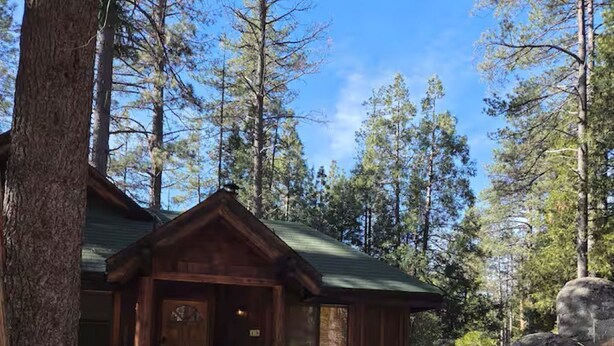 A cabin with a front porch, a green roof, and a stone wall. - Comfortable 1-bedroom Suite (Idyllwild-Pine Cove)