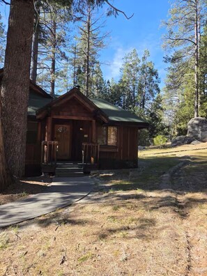 Eine Hütte mit einer Veranda, einem grünen Dach und einer Steinwand.