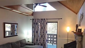 A living room with a sofa, coffee table, TV, and a stone fireplace. - Comfortable 1-bedroom Suite (Idyllwild-Pine Cove)