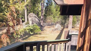 A wooden deck with a railing, overlooking a natural landscape with trees and rocks. - Comfortable 1-bedroom Suite (Idyllwild-Pine Cove)