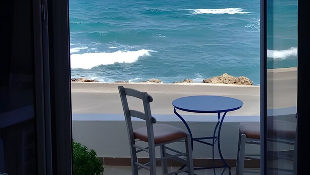 Un balcone con tavolo e sedie affacciato su una spiaggia e l'oceano.