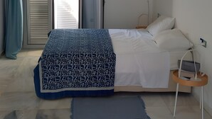 Una camera da letto con un letto, un ventilatore a soffitto, un condizionatore d'aria, una finestra con tende e un comodino con una lampada.