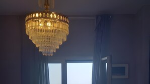 Una stanza con un tavolo in legno, sedie, un lampadario, vista sul mare e una porta che dà all'esterno.