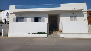 Un edificio moderno, bianco, con tetto piatto, ingresso centrale e un piccolo portico.