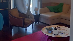 Un soggiorno con un lampadario, un divano, una poltrona, un tavolino e una libreria.