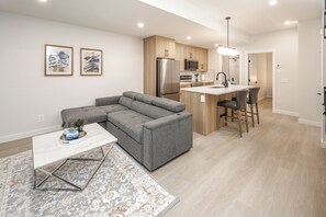 Una cocina moderna con armarios de madera, electrodomésticos de acero inoxidable y una isla central con taburetes de bar.