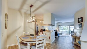 Un comedor con mesa y sillas de madera, una cocina con refrigerador y estufa, y un balcón con vistas.