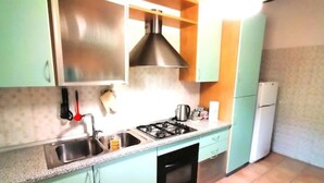 Una cucina con piano cottura a gas, lavello e frigorifero.