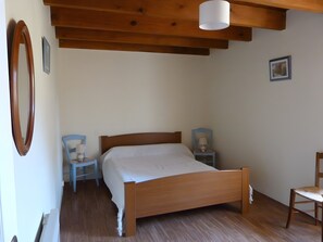 A bedroom with a wooden bed, two bedside tables with lamps, a chair, and a wooden ceiling. - Quercy House: Private Terrace, Garden & Balcony in the Célé Valley (Corn)