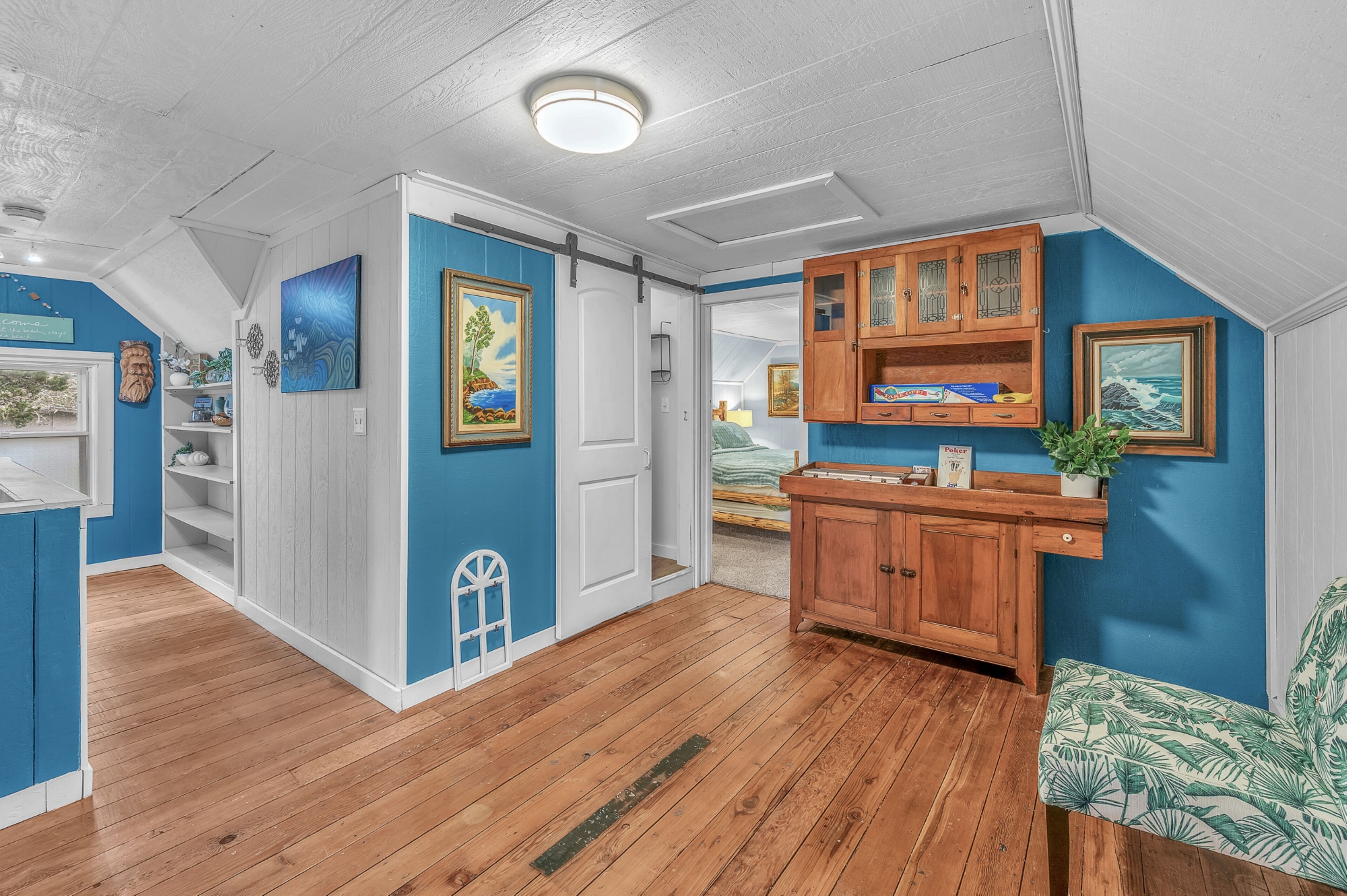 A room with a wooden floor, a white door, a blue wall, and a wooden cabinet with glass doors.