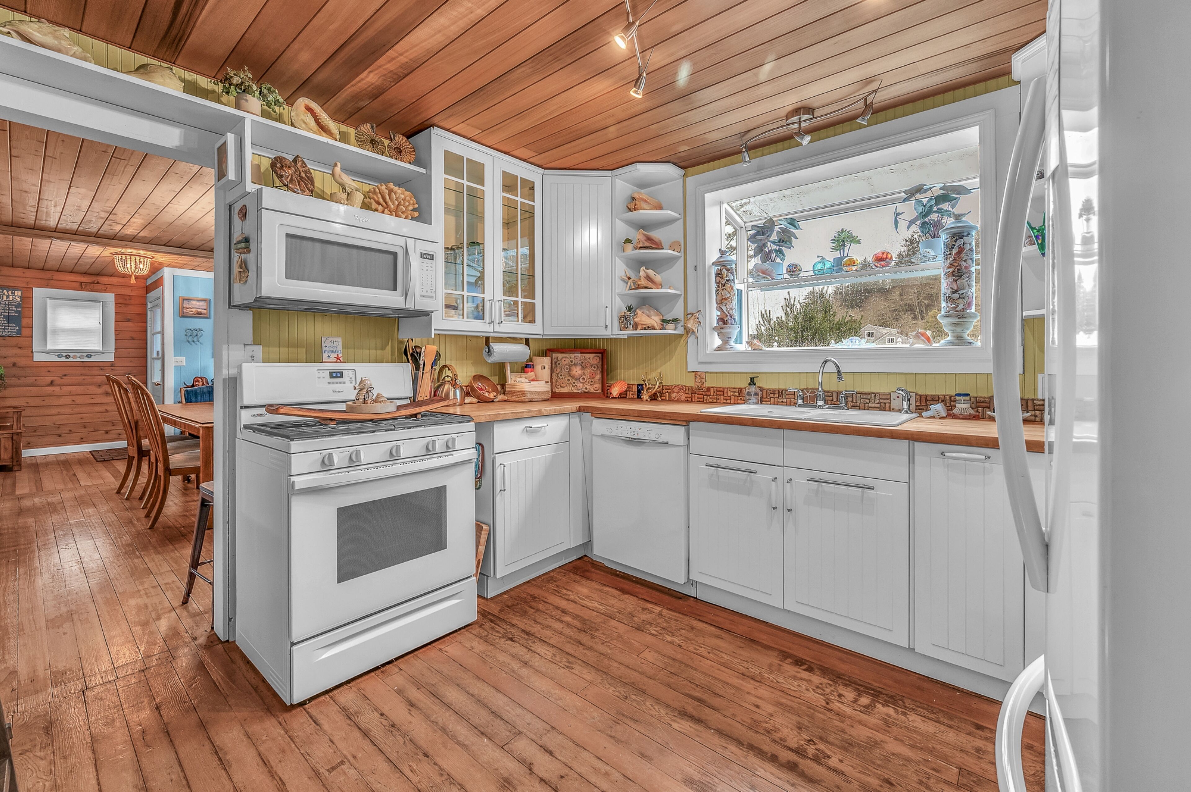 Une cuisine avec des meubles blancs, une cuisinière, un four à micro-ondes et une fenêtre donnant sur l’extérieur.