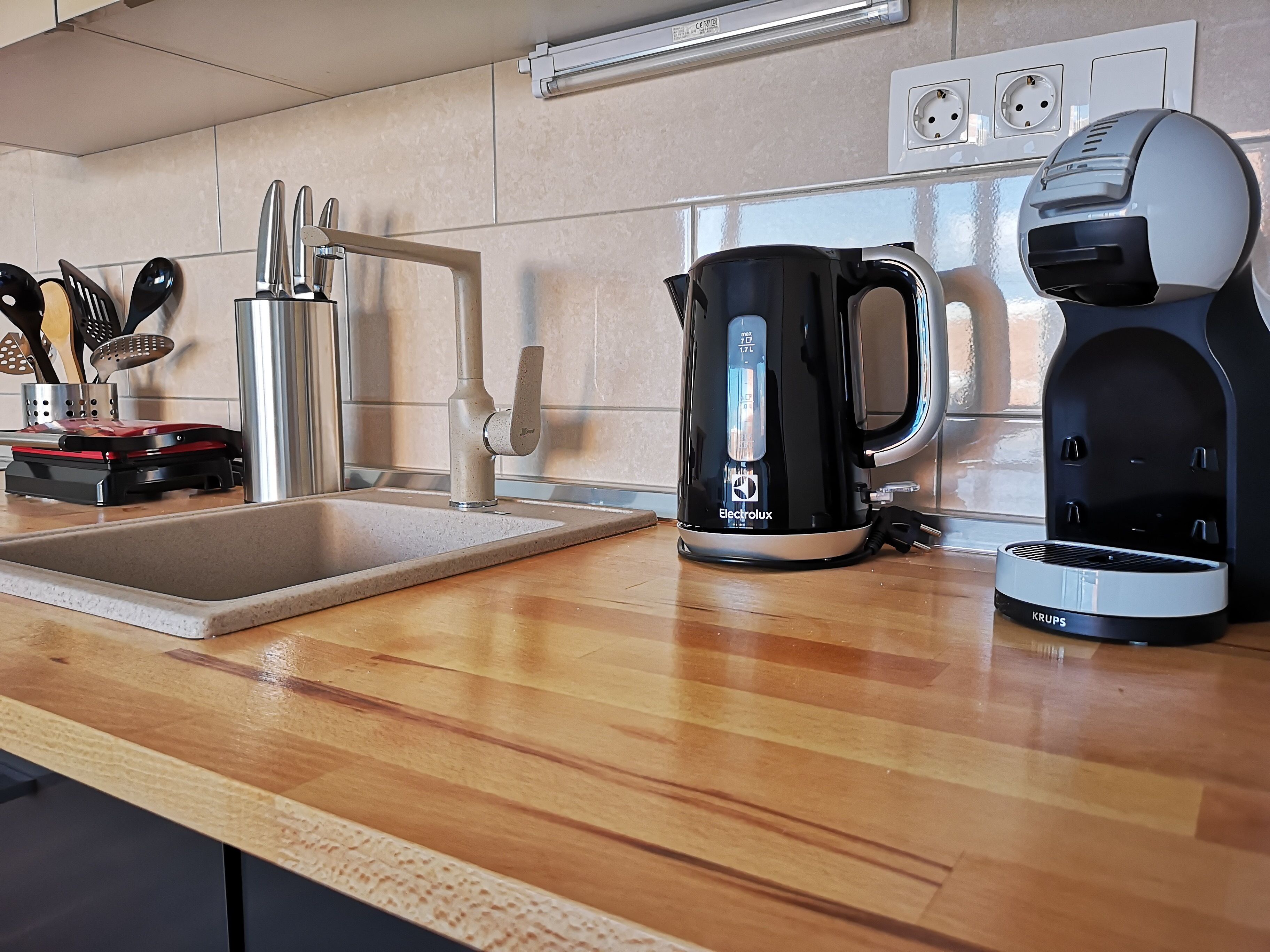 Een keuken met een moderne kraan, een koffiezetapparaat en een Krups waterkoker.