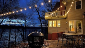 Una casa con patio coperto, barbecue e luci a stringa.