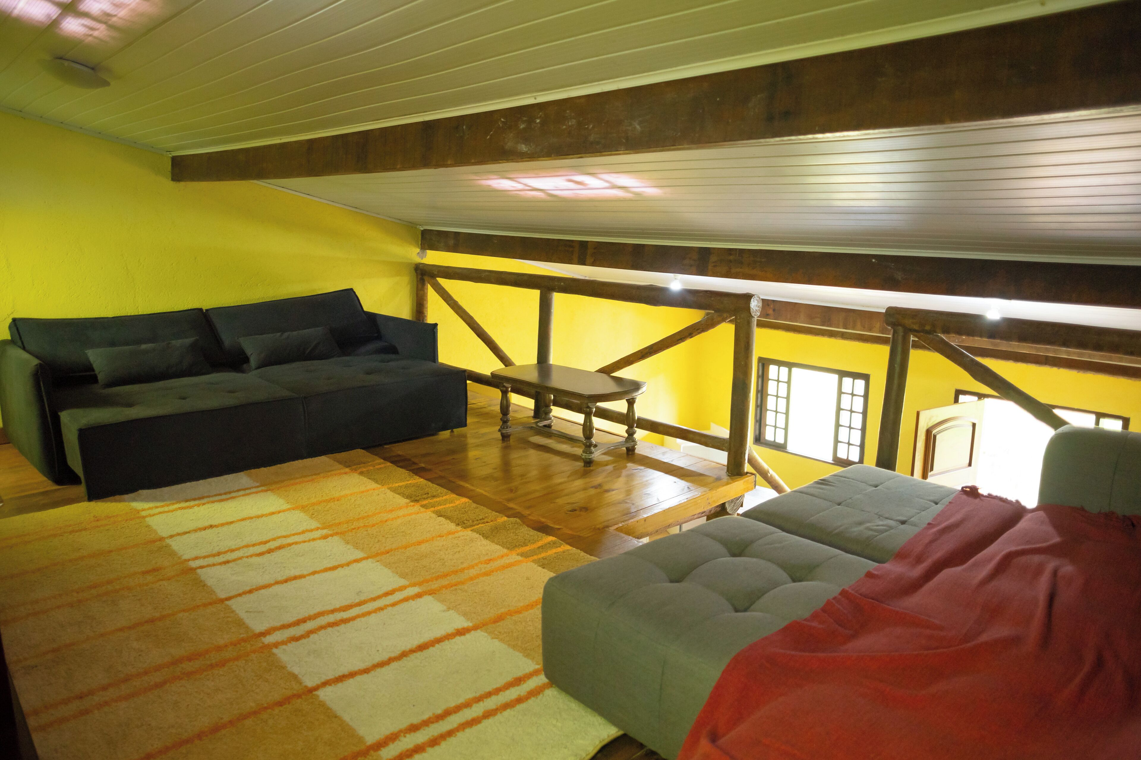 Una habitación con techo de madera, un sofá, una silla y una cama.