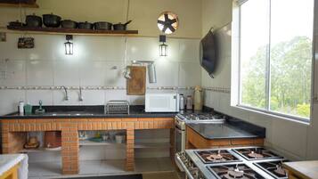 Cocina con mostrador de ladrillo, estufa, microondas y luces colgantes.