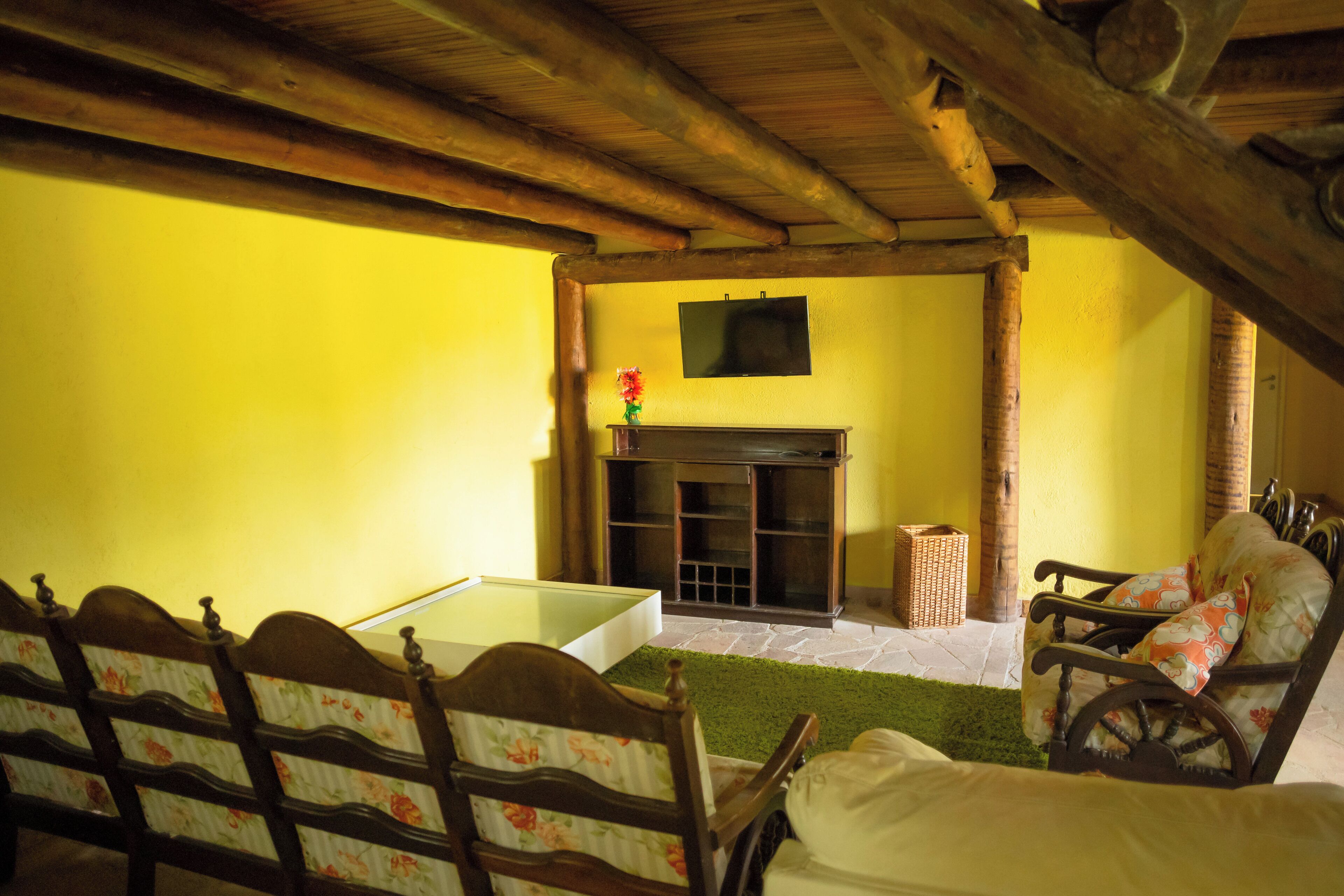 A room with a fireplace, wooden beams, a sofa, and a table.