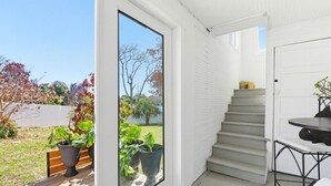 En modern inredning med en trappa som leder upp till en uteplats, stora fönster och krukväxter.