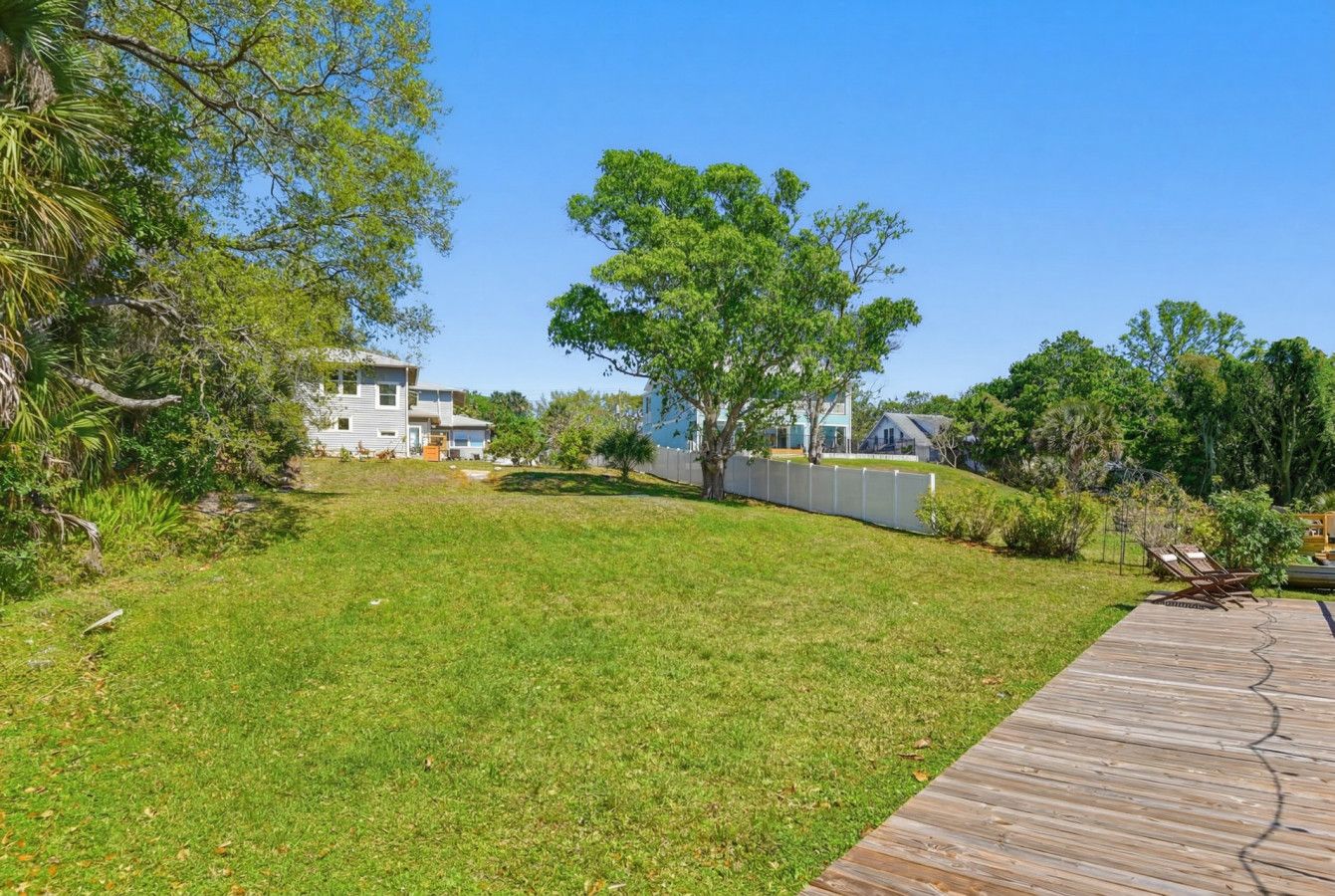 A grassy yard with a wooden deck and a house in the background.