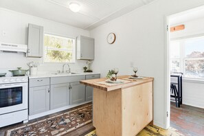 Una cocina con una isla central, estufa, fregadero y armarios.
