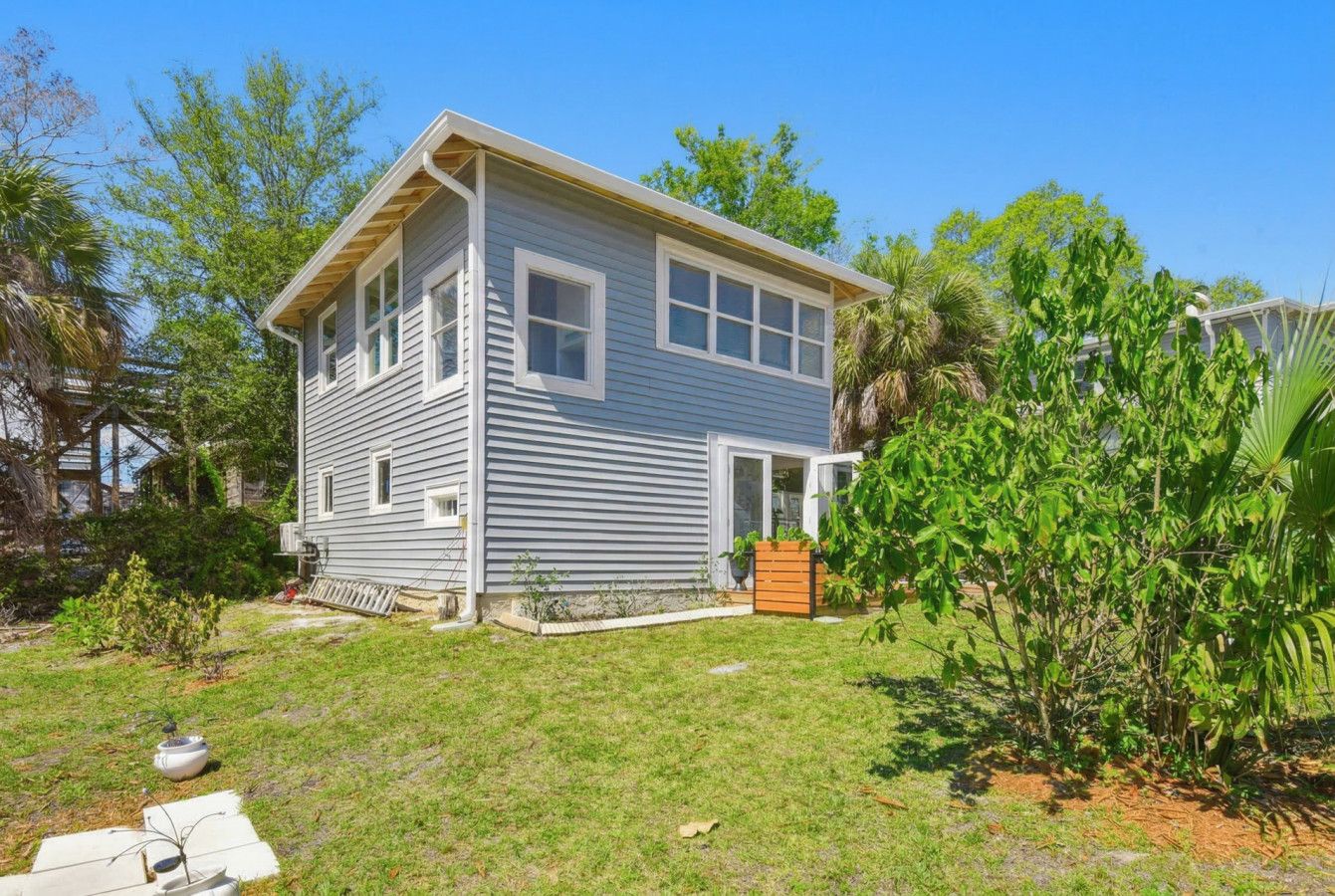 A two-story house with a front porch, a small garden, and a wooden deck.